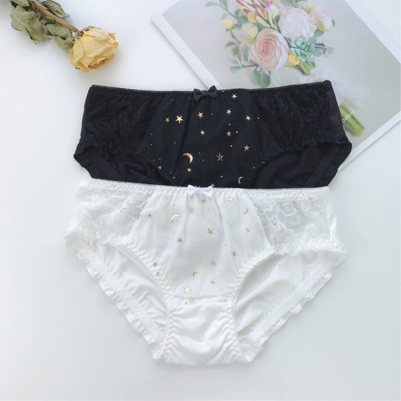Two pairs of whimsical panties, one in black and one in white, with crescent and star patterns and chiffon fabric on the front.