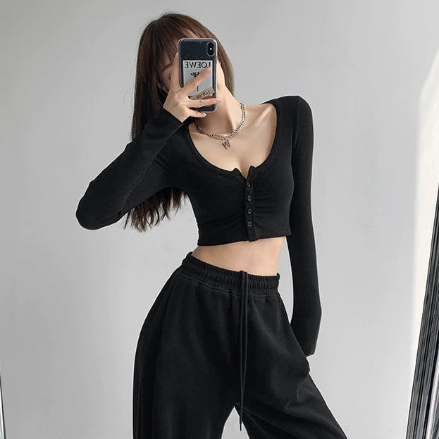 Femboy wearing a U-neck black long-sleeve crop top and black pants against a plain background