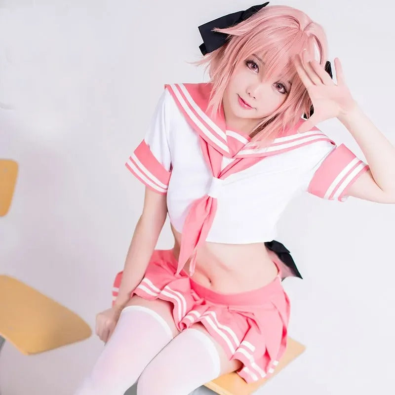 femboy in a pink and white Sailor Seifuku Astolfo Cosplay Outfit with a black bow, sitting on a chair.